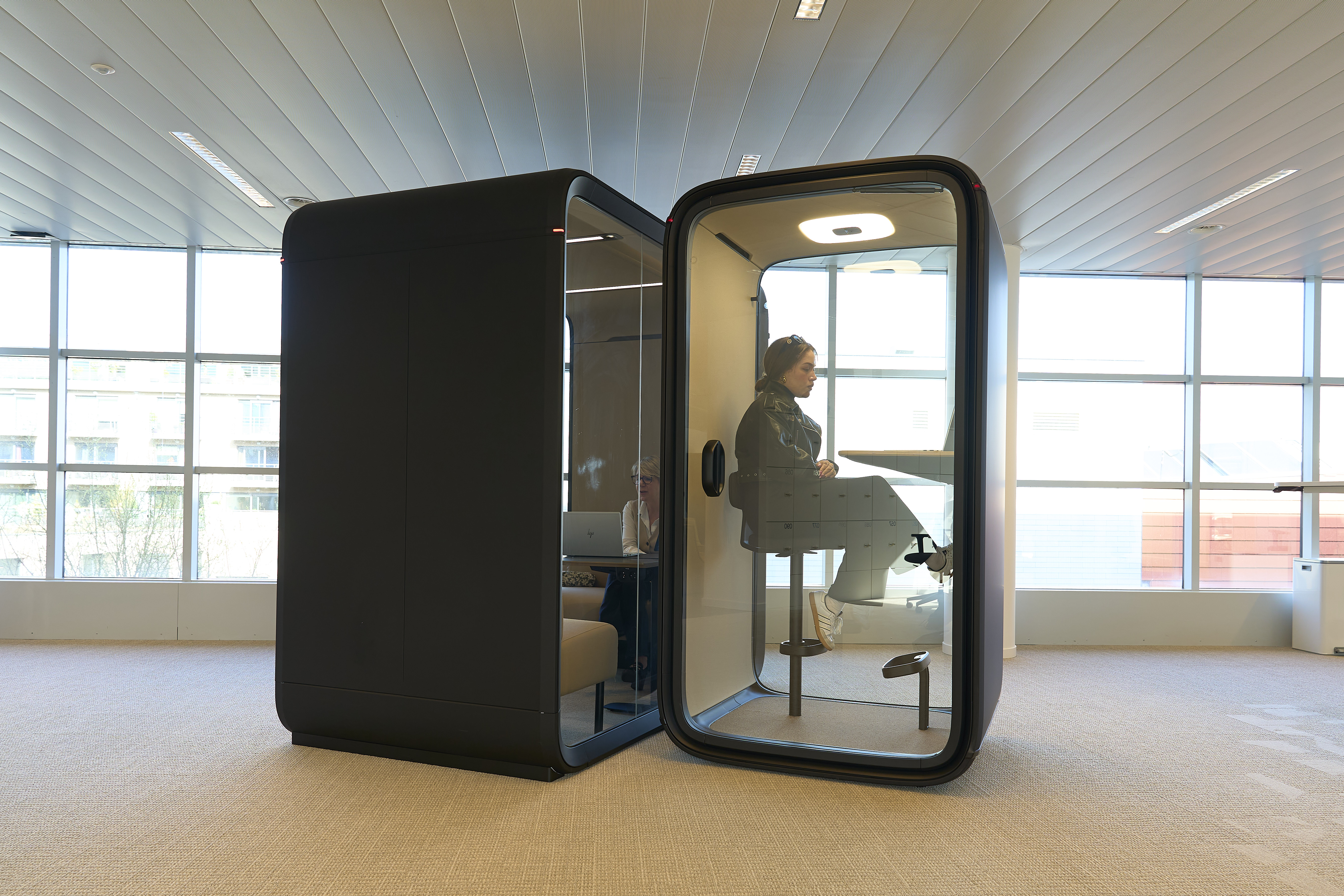 une femme assise dans une cabine en verre