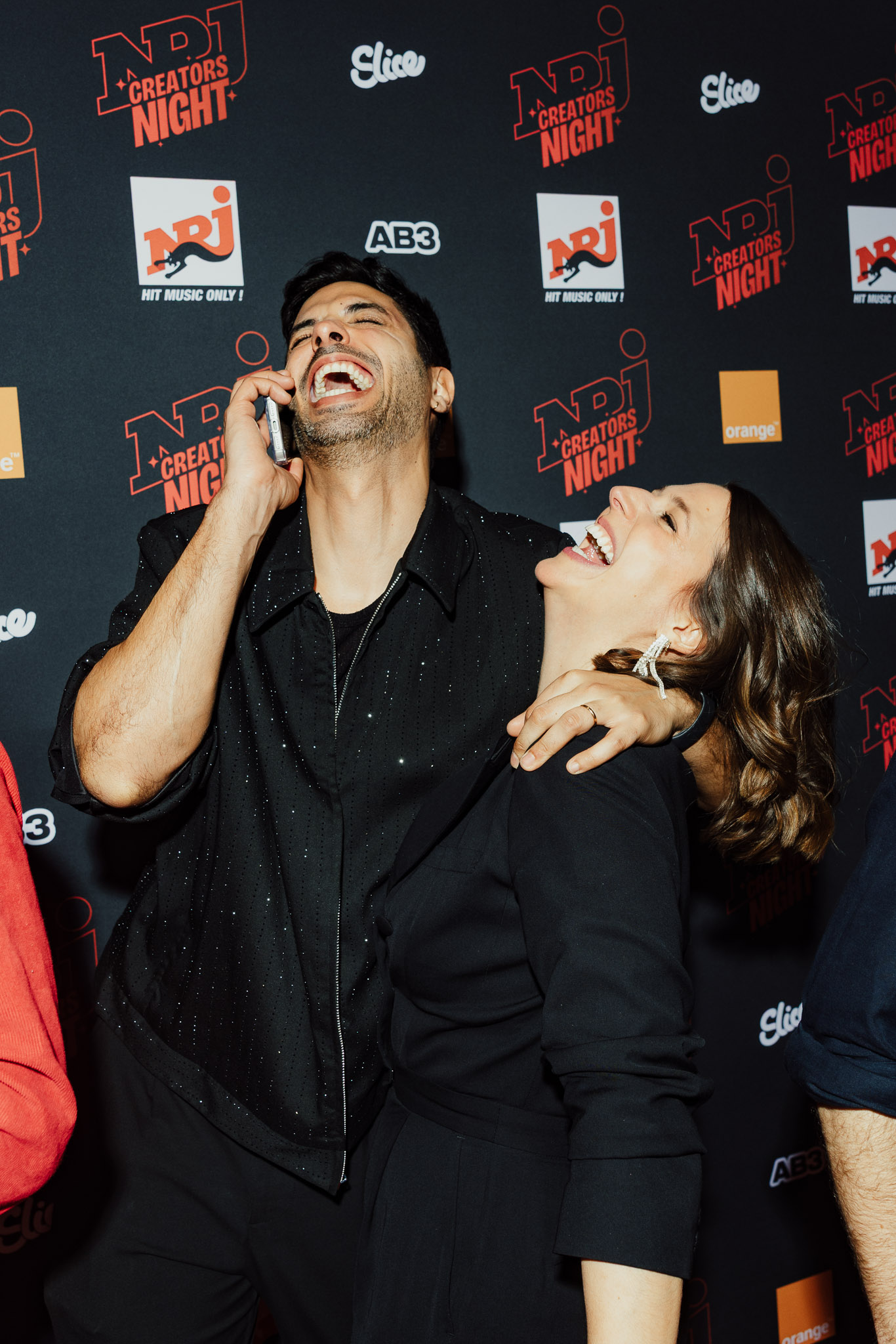 a man and a woman laughing at a red carpet event