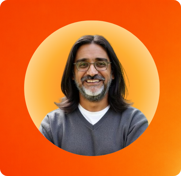 un homme aux longs cheveux et portant des lunettes souriant